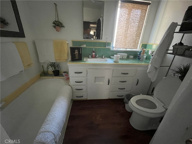 full bath with a bathing tub, backsplash, toilet, and vanity