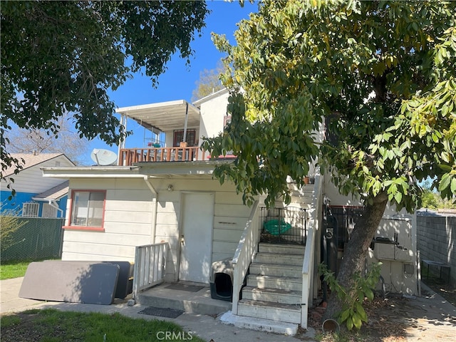 back of house featuring a balcony and fence