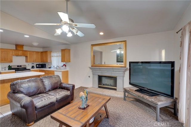 living area with lofted ceiling, a fireplace with raised hearth, recessed lighting, and ceiling fan