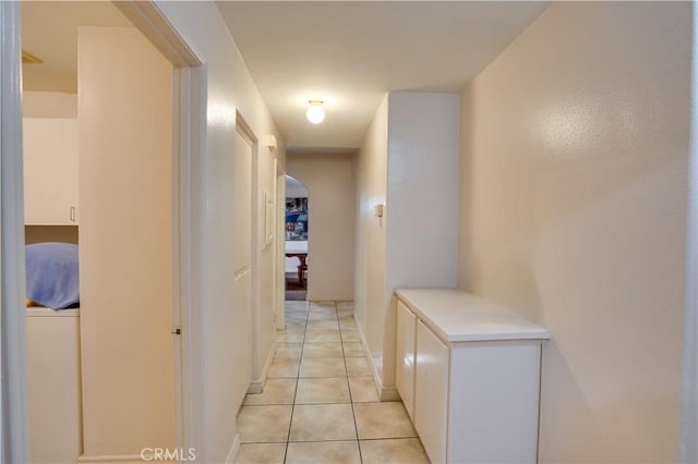 hallway with arched walkways and light tile patterned flooring