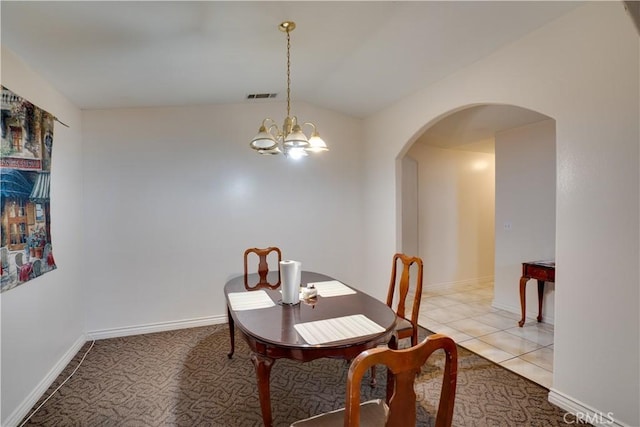 dining area with light tile patterned floors, visible vents, an inviting chandelier, arched walkways, and vaulted ceiling