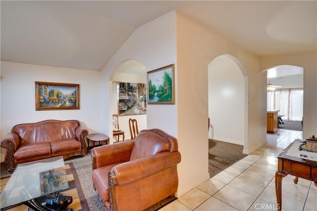 living area featuring arched walkways, light tile patterned flooring, baseboards, light colored carpet, and vaulted ceiling