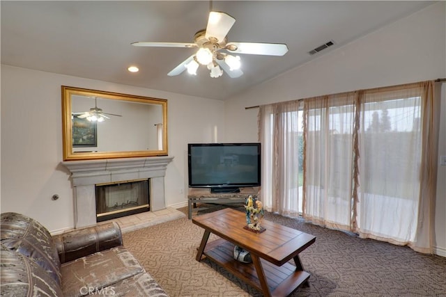 living room featuring carpet, visible vents, lofted ceiling, a fireplace with raised hearth, and ceiling fan