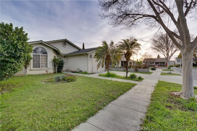 view of front of home featuring concrete driveway, a garage, a front lawn, and stucco siding