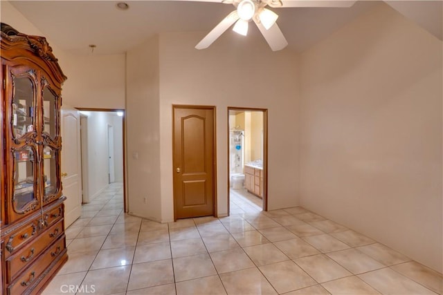 spare room with light tile patterned flooring, ceiling fan, and a towering ceiling