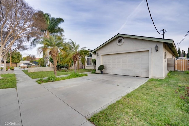 view of front of home with a front yard, stucco siding, a garage, driveway, and a gate