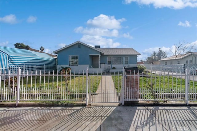 view of front of home featuring stucco siding, a fenced front yard, a front lawn, and a gate