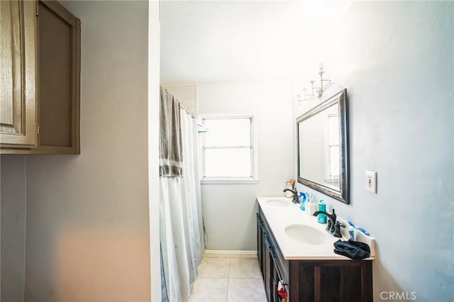 full bath with tile patterned flooring, double vanity, baseboards, and a sink