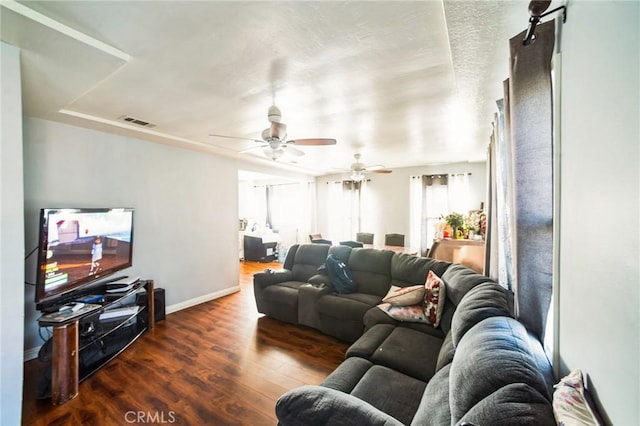 living room featuring visible vents, baseboards, wood finished floors, and a ceiling fan