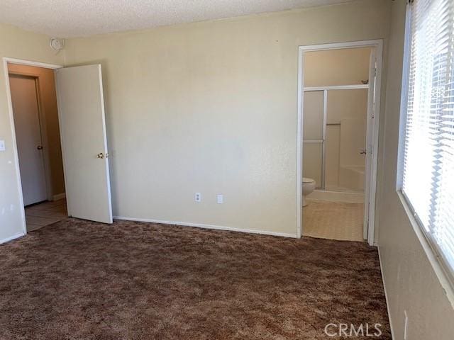 unfurnished bedroom featuring connected bathroom, carpet floors, and a textured ceiling