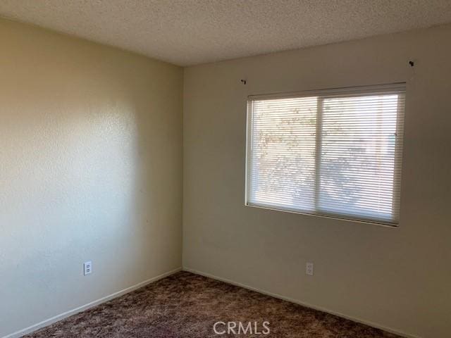 carpeted empty room featuring a textured ceiling