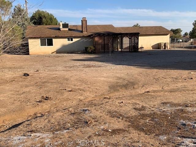 rear view of house with cooling unit, fence, and stucco siding