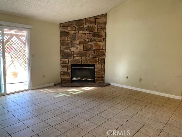 unfurnished living room featuring plenty of natural light, a textured ceiling, a stone fireplace, and vaulted ceiling