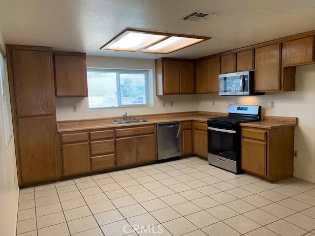 kitchen featuring visible vents, stainless steel appliances, light countertops, and a sink