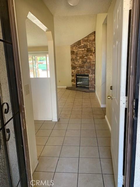 hallway with light tile patterned flooring, baseboards, and vaulted ceiling