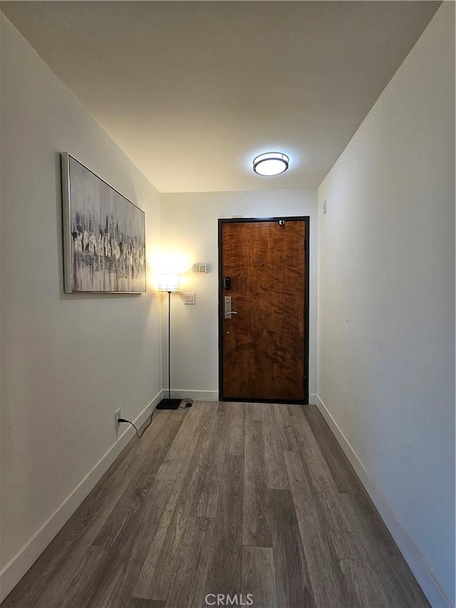 corridor featuring baseboards and wood finished floors