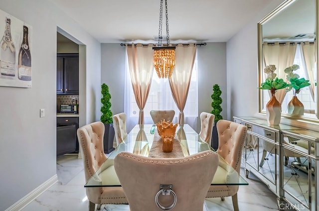 dining area featuring baseboards, marble finish floor, and a chandelier