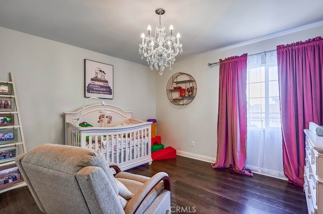 bedroom featuring a chandelier, a nursery area, baseboards, and wood finished floors