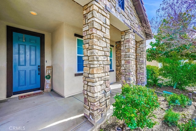 view of exterior entry featuring stone siding and stucco siding