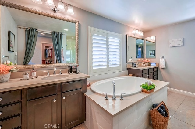 bathroom with baseboards, a bath, vanity, and tile patterned flooring