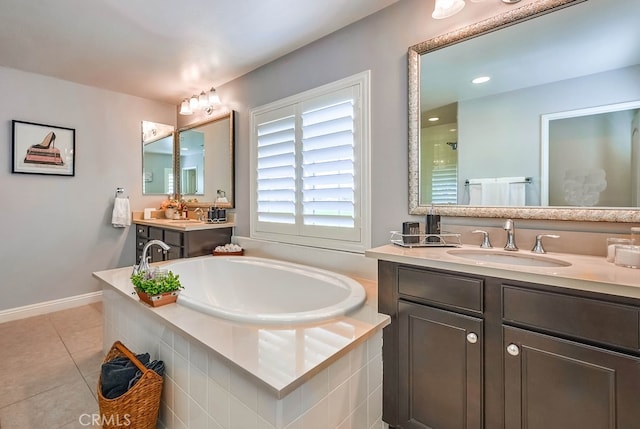 full bathroom with two vanities, a sink, tile patterned flooring, baseboards, and a bath