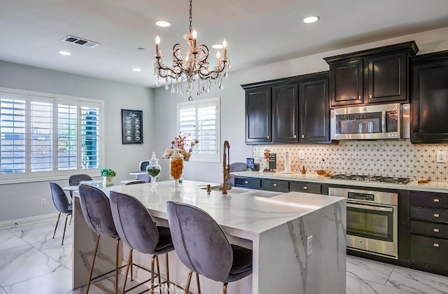 kitchen with decorative backsplash, light stone counters, visible vents, and stainless steel appliances