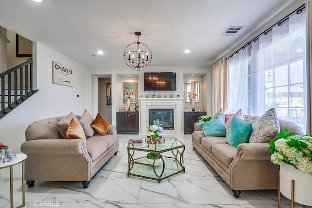 living room featuring stairway, visible vents, recessed lighting, a glass covered fireplace, and a notable chandelier