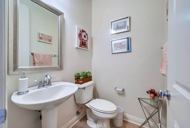 bathroom featuring a sink, baseboards, and toilet