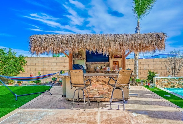 view of patio with outdoor dry bar and fence