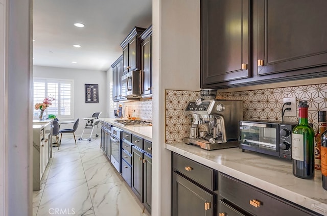 kitchen featuring marble finish floor, light stone counters, recessed lighting, stainless steel appliances, and decorative backsplash