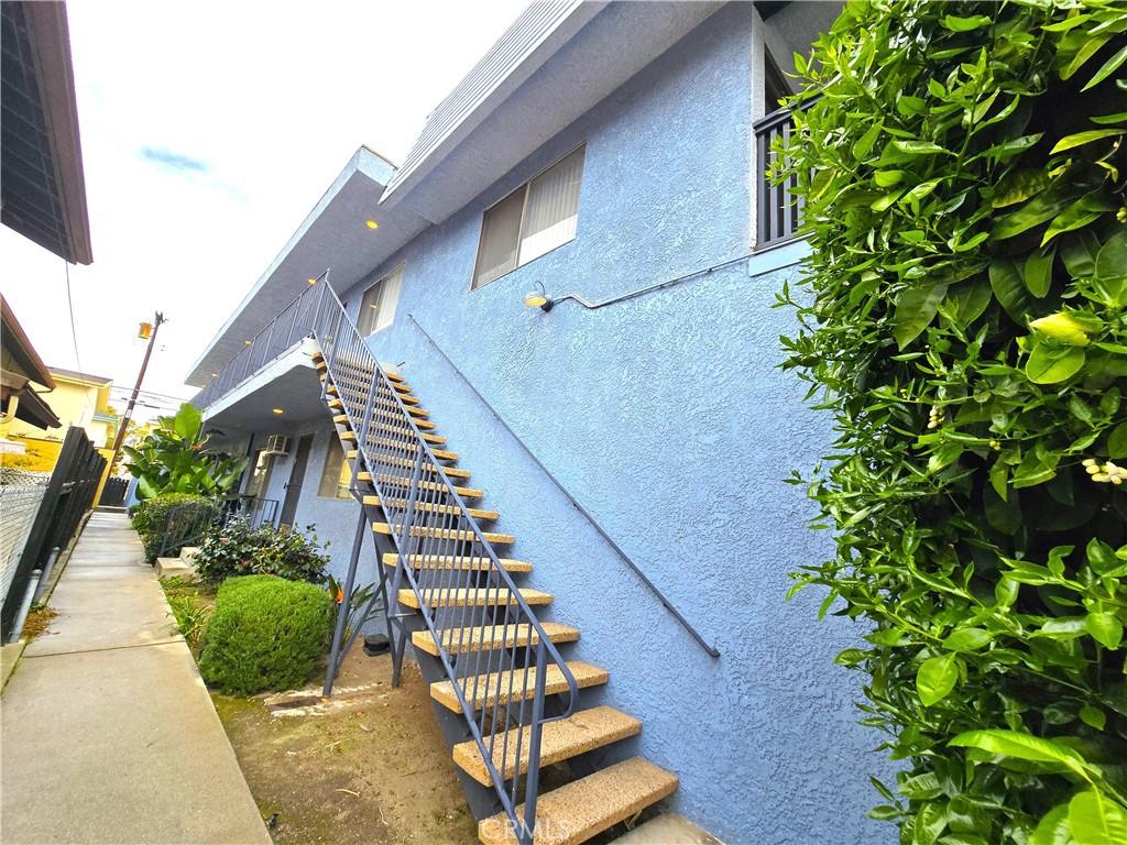 exterior space featuring stairway, fence, and stucco siding