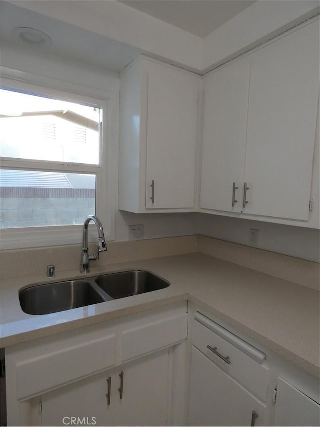 kitchen featuring white cabinetry, light countertops, and a sink