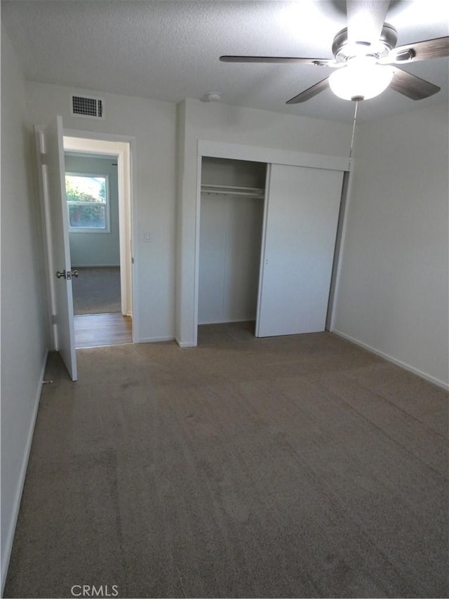 unfurnished bedroom with visible vents, ceiling fan, carpet, a closet, and a textured ceiling