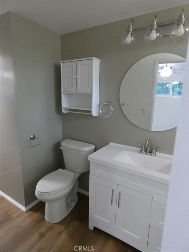 bathroom with toilet, vanity, baseboards, and wood finished floors