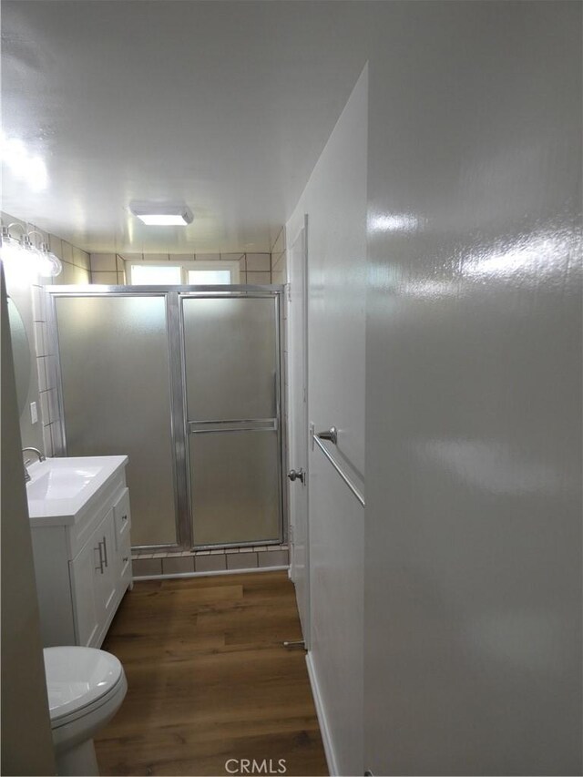 bathroom with vanity, a shower stall, toilet, and wood finished floors