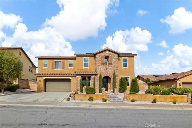 mediterranean / spanish-style home featuring fence, stucco siding, concrete driveway, a garage, and stone siding