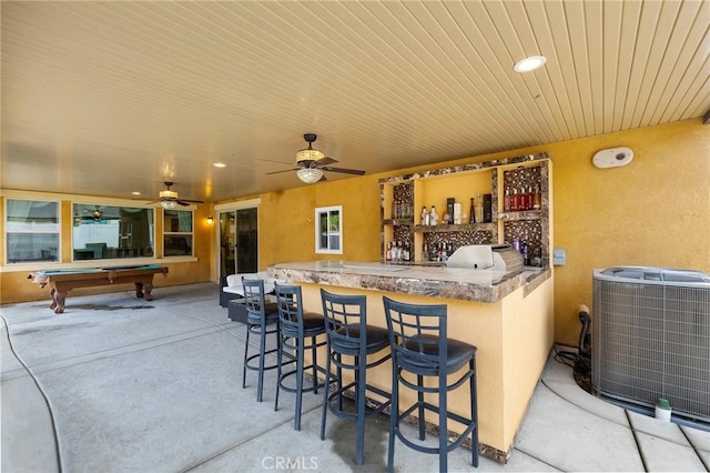 view of patio featuring central air condition unit, an outdoor kitchen, ceiling fan, and outdoor wet bar