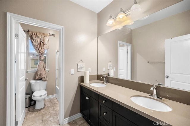 bathroom featuring a sink, baseboards, toilet, and double vanity