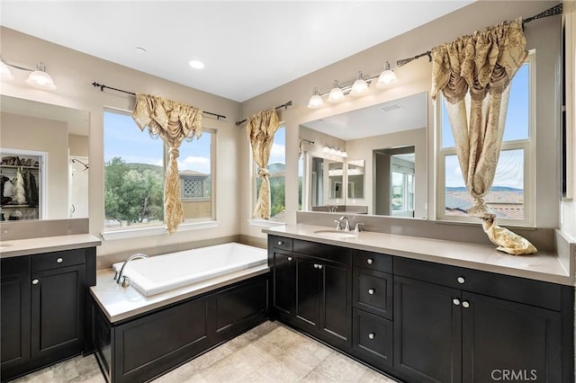 full bathroom featuring vanity, a garden tub, and a healthy amount of sunlight