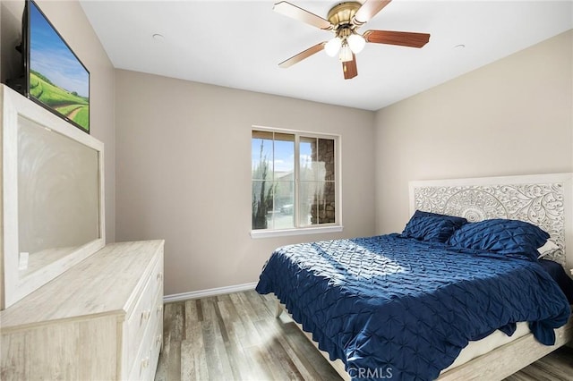 bedroom featuring baseboards, wood finished floors, and a ceiling fan