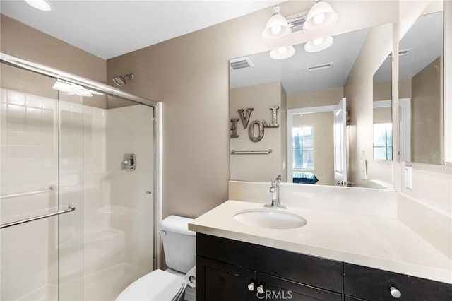 bathroom featuring visible vents, vanity, toilet, and a shower stall