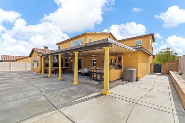 rear view of property featuring fence, central AC, stucco siding, a patio, and a gate