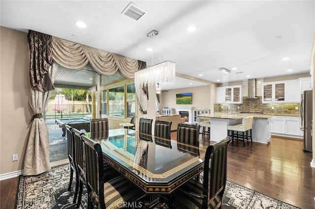 dining area with visible vents, baseboards, dark wood finished floors, recessed lighting, and a warm lit fireplace