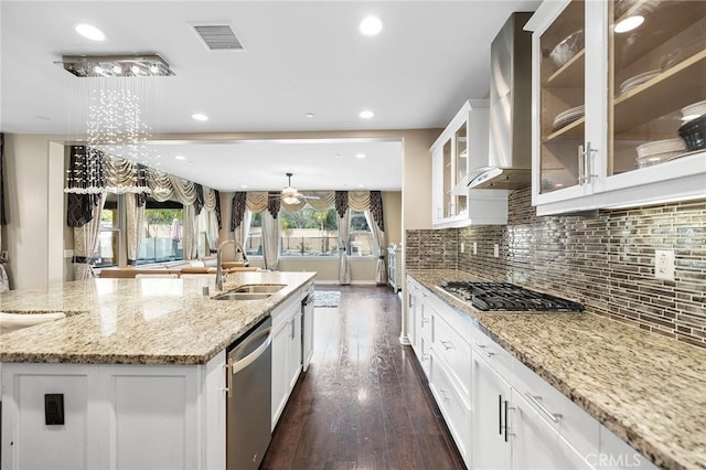 kitchen featuring wall chimney range hood, decorative backsplash, a large island, stainless steel appliances, and a sink