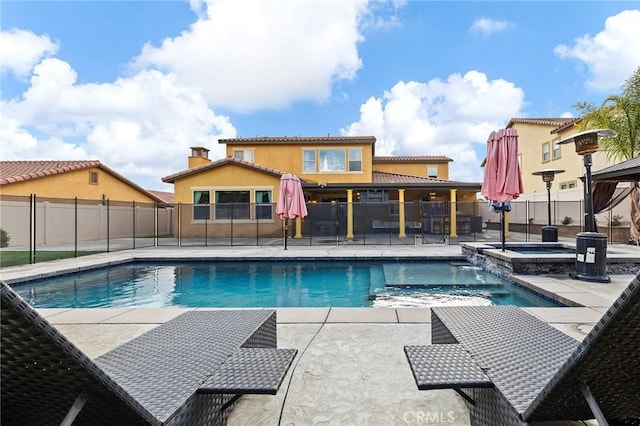 view of swimming pool featuring a patio area, a pool with connected hot tub, and fence