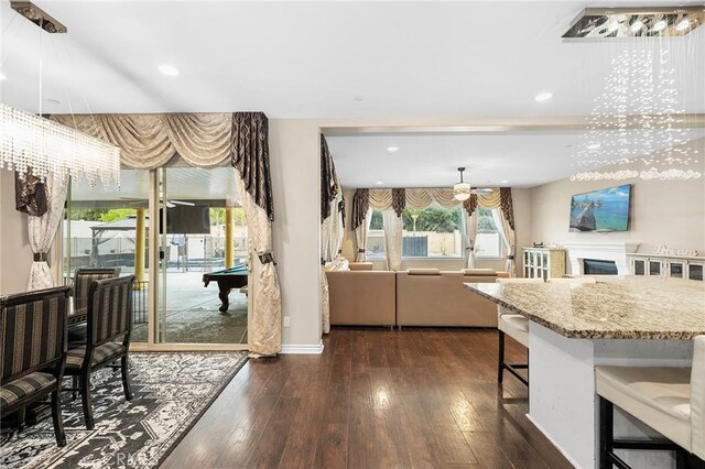 kitchen with recessed lighting, a kitchen bar, dark wood finished floors, and a fireplace