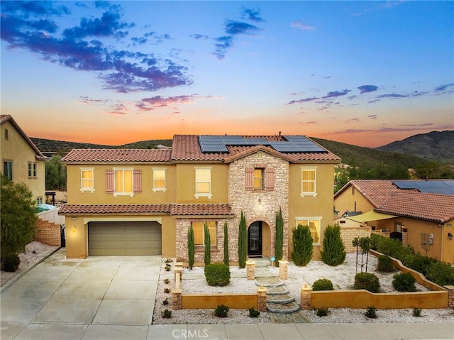 mediterranean / spanish-style home featuring fence, a tiled roof, concrete driveway, stucco siding, and stone siding