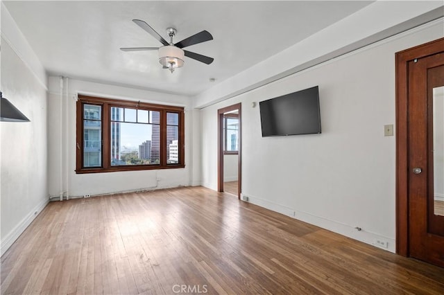 unfurnished living room featuring baseboards, wood-type flooring, and a ceiling fan