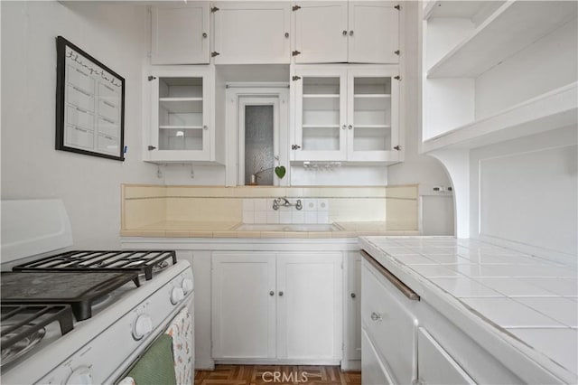 kitchen with white cabinetry, tile counters, white gas stove, and a sink