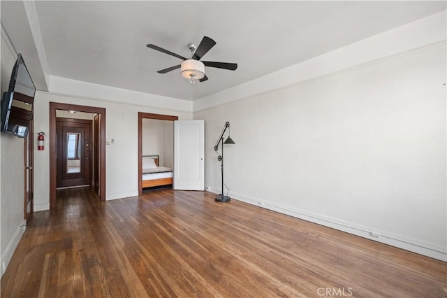 unfurnished room featuring baseboards, wood finished floors, and a ceiling fan